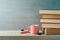 Back to school concept with coffee cup and books on wooden shelf background