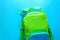 Back to school concept. Green backpack with school supplies on blue background. Top view.