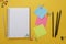 Back to school concept. Open empty notebook, school supplies, sticky notes. Yellow background. Flat lay, top view