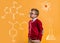 Back to school. Confident schoolboy in big glasses standing by the yellow school wall with chemical formulas on it