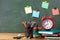 Back to school or education concept with alarm clock, paper notebooks and school supplies against blackboard background