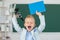 Back to school. Excited schoolboy pupil with microscope and book. Funny face of little student of primary school study