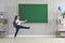 Back to school. Funny schoolgirl with a book is walking on the background of the school blackboard.