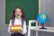 Back to school. Funny schoolgirl with books in her hands laughs in class.