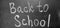 Back to School hand written in white chalk on a blackboard. Black and white monochrome photography. Letters and words. Reminder