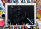 Back to school inscription written on chalkboard with kids supplies for modern primary education, color pencils, paints and other