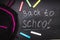 Back to school message on Blackboard inscribed with colorful chalk for background. Backpack.