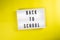 Back To School message on lightbox on yellow background isolated