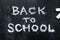 Back To School phrase written on a black wood background, top view.