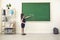 Back to school. Rear view of a schoolgirl in chalk writes on a school chalkboard in class.