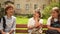 Back to school. Schoolchildren with satchels are sitting on a bench in the schoolyard. Boy and two girls talking while