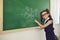 Back to school. A schoolgirl with glasses writes on a school board in a classroom at a lecture.