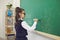 Back to school. A schoolgirl with glasses writes on a school board in a classroom at a lecture.