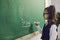 Back to school. A schoolgirl with glasses writes on a school board in a classroom at a lecture.