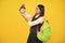 Back to school. Teenager schoolgirl with backpack hold clock alarm, time to learn. School children on  yellow