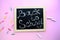 Back to school text on a black board with a wooden frame written with chalk hand on a pink background and stationery.