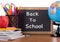 Back To School text on a blackboard with school supplies