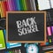 Back to school text on blackboard with wooden frame on a background with 3d realistic supplies for education.