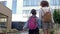 Back to school. Two schoolgirls of different ages with backpacks go to school, holding hands. The older sister takes the