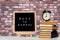 Back to school words on a letter board with books and vintage alarm clock against brick wall background