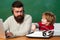 Back to school. Young boy doing his school homework with his father. Teacher helping kids with their homework in