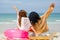 Back of two woman look like friends sit on beach and look to the sea with wave hands forward side during holiday or vacation