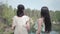 Back of two young woman standing in the top of mountain and looking at amazing view of hill, lake, forest and greens