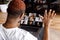 Back view of african american male freelancer waving hello to coworkers on video meeting, using laptop. Stylish friendly