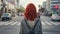 Back view of anonymous female with red hair standing near crosswalk