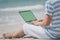 Back view of asian man on holiday on the beach and working with a laptop. Close-up of hand on laptop