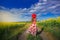 Back view of attractive young woman in hat with long hair in sunflower field enjoying nature,rainbow mountain view