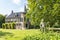 The back view of a beautiful castle with a stone statue of Cupid in the foreground in a park in Lisse, the Netherlands