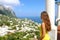 Back view of beautiful girl looking at Capri sight from terrace, Capri Island, Italy