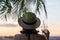 Back view of a beautiful girl with mineral water in a glass  in a straw hat against the background of the sea in branches of palm