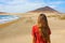 Back view of beautiful girl in red dress standing on the beach, El Medano, Tenerife