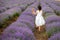 Back view of a beautiful little girl enjoying and running between rows of blooming lavender