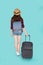 Back view beautiful young asian woman pulling suitcase isolated on blue background