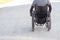 Back view of Black man in wheelchair riding along wide road