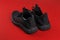 Back view of black mesh sneakers against red background. Pair of modern breathable shoes for hot summer. New comfortable men shoes