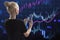 Back view of blonde european woman using mobile phone with glowing growing forex chart on blurry background. Trade, finance and