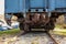 Back view of a blue railroad car on tracks. The car coupler mechanism and undercarriage are rusted.