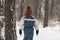 Back view Boy in winter clothes walks through snow-kept forest. Child in winter on the street