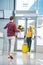 Back view of boyfriend with flowers meeting beautiful girlfriend with suitcase