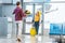 Back view of boyfriend with flowers meeting happy girlfriend with suitcase