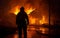 Back view of a brave fireman standing in front of a house engulfed in flames, under the dark night sky.