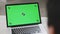 Back view of businessman look green screen laptop in office. Close up shot of modern chroma key green screen laptop