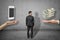 Back view of businessman standing between two big hands, woman`s hand levitating iPhone, and man`s hand levitating stack