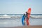 Back view of caring family of surfers holding surfboards