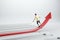 Back view of casual young man balancing on growing red arrow on light background. Improving business and changing direction