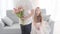 Back view of Caucasian boy in white T-shirt and jeans coming to pretty girl with a bouquet of tulips. Surprised child in